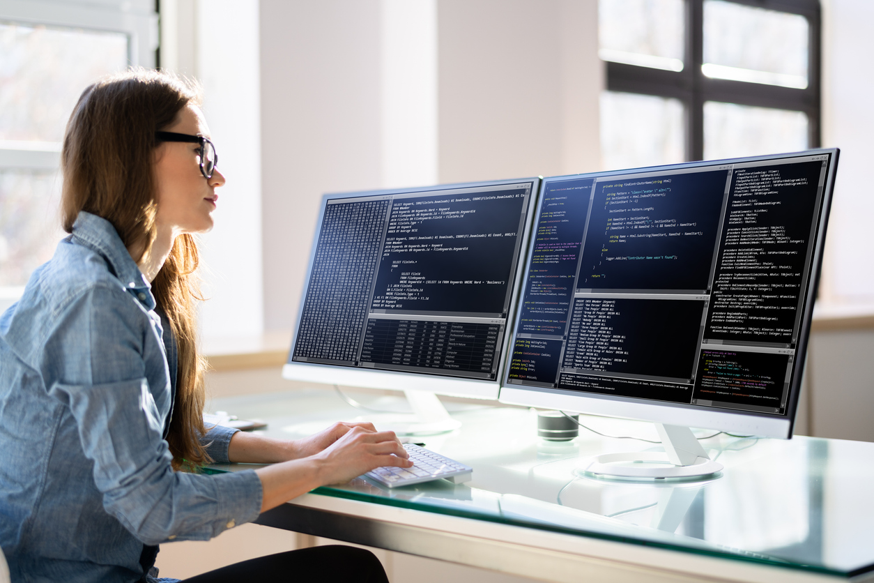 A Software Engineer Examines Code on a Pair of Monitors.