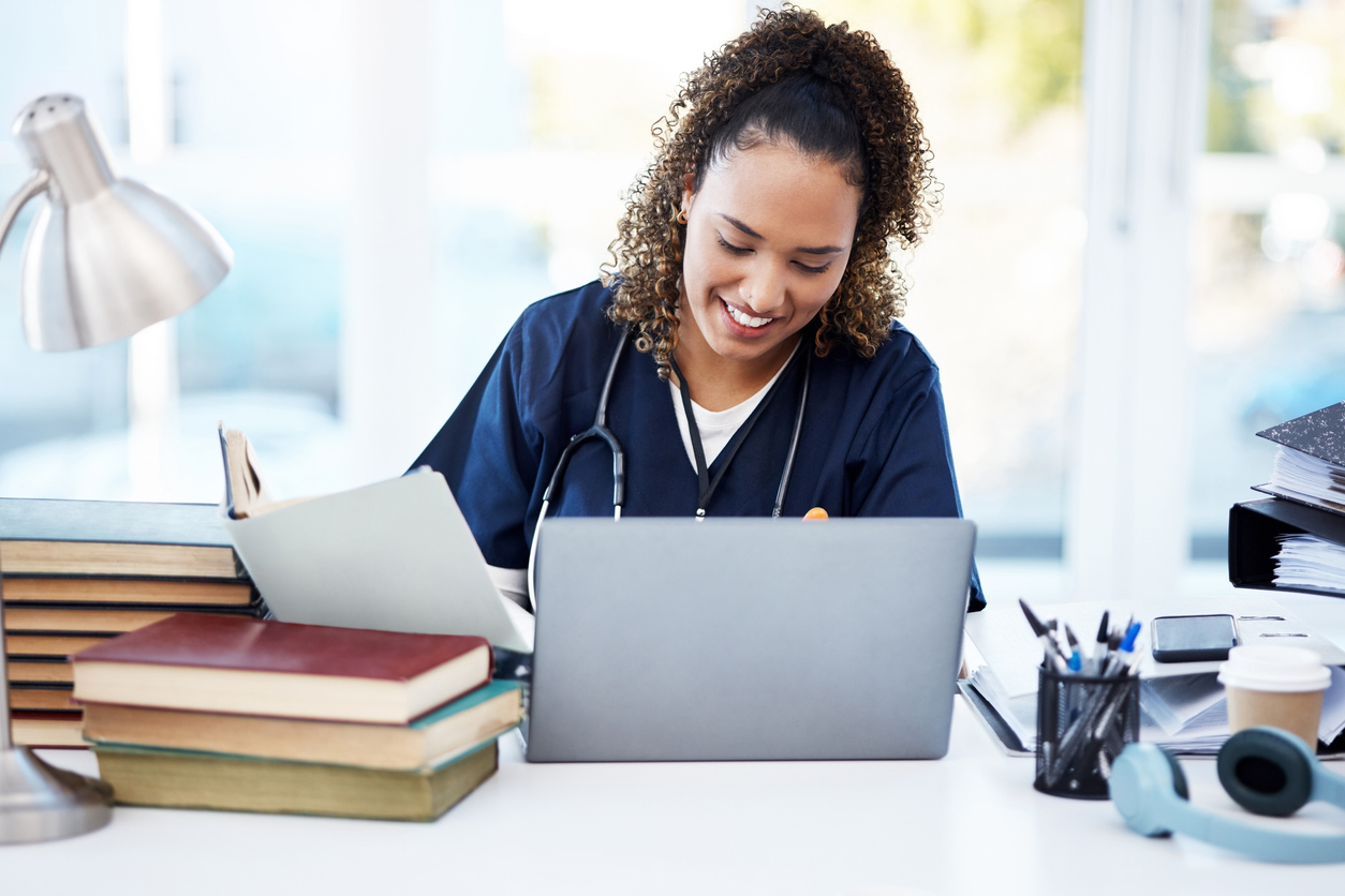 Nurse in Scrubs Smiling and Working on a Laptop..jpg