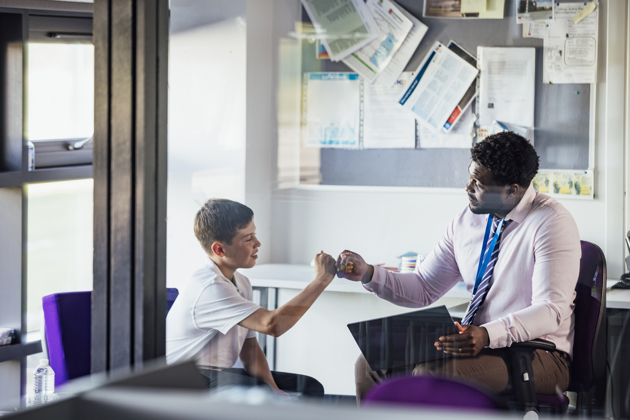 A school counselor bumps fists with a student.