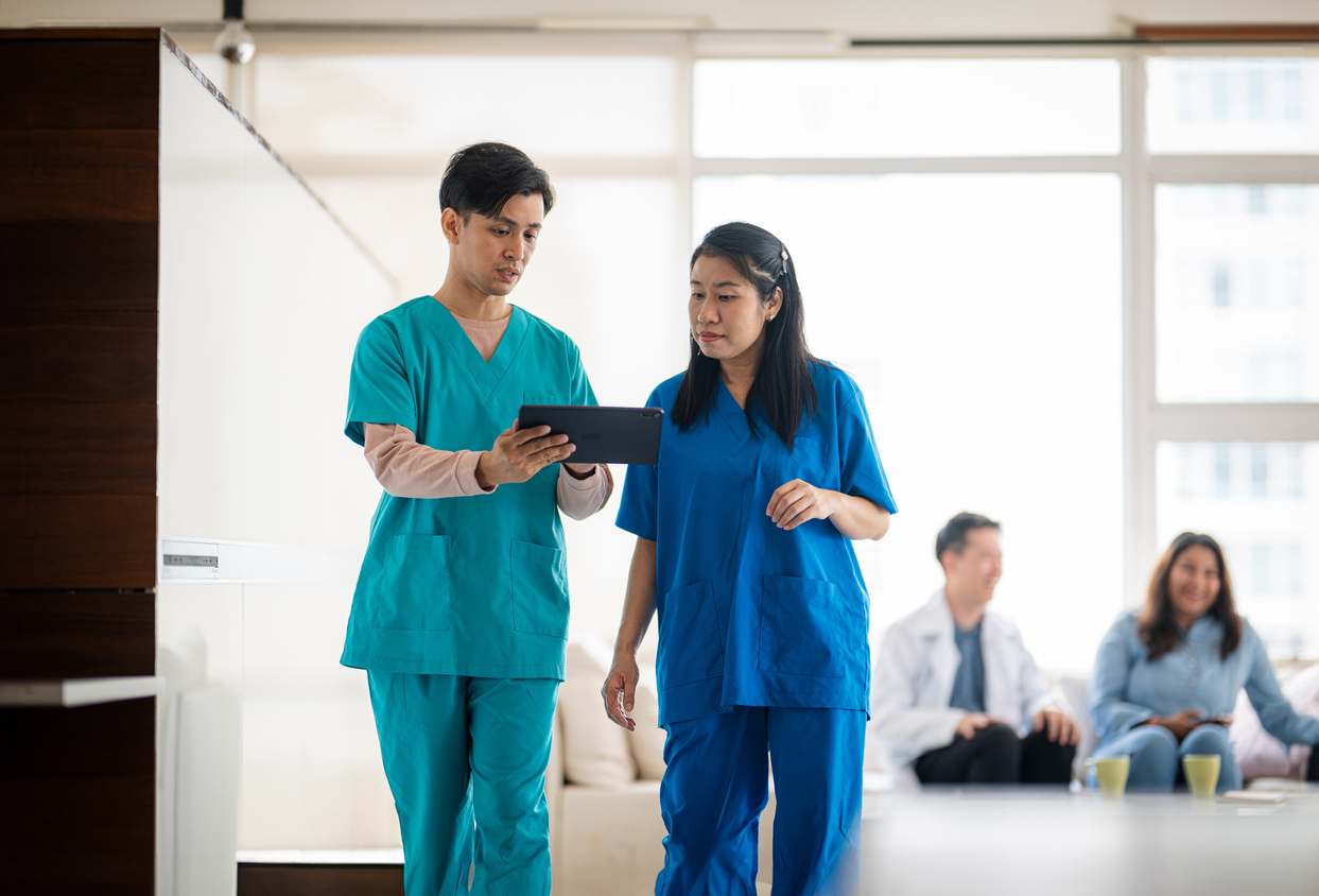Nurses Walking and Looking at a Tablet in a Medical Facility.