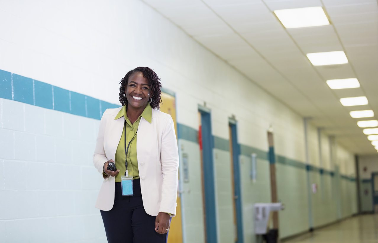 A smiling school superintendent stands in a school hallway.