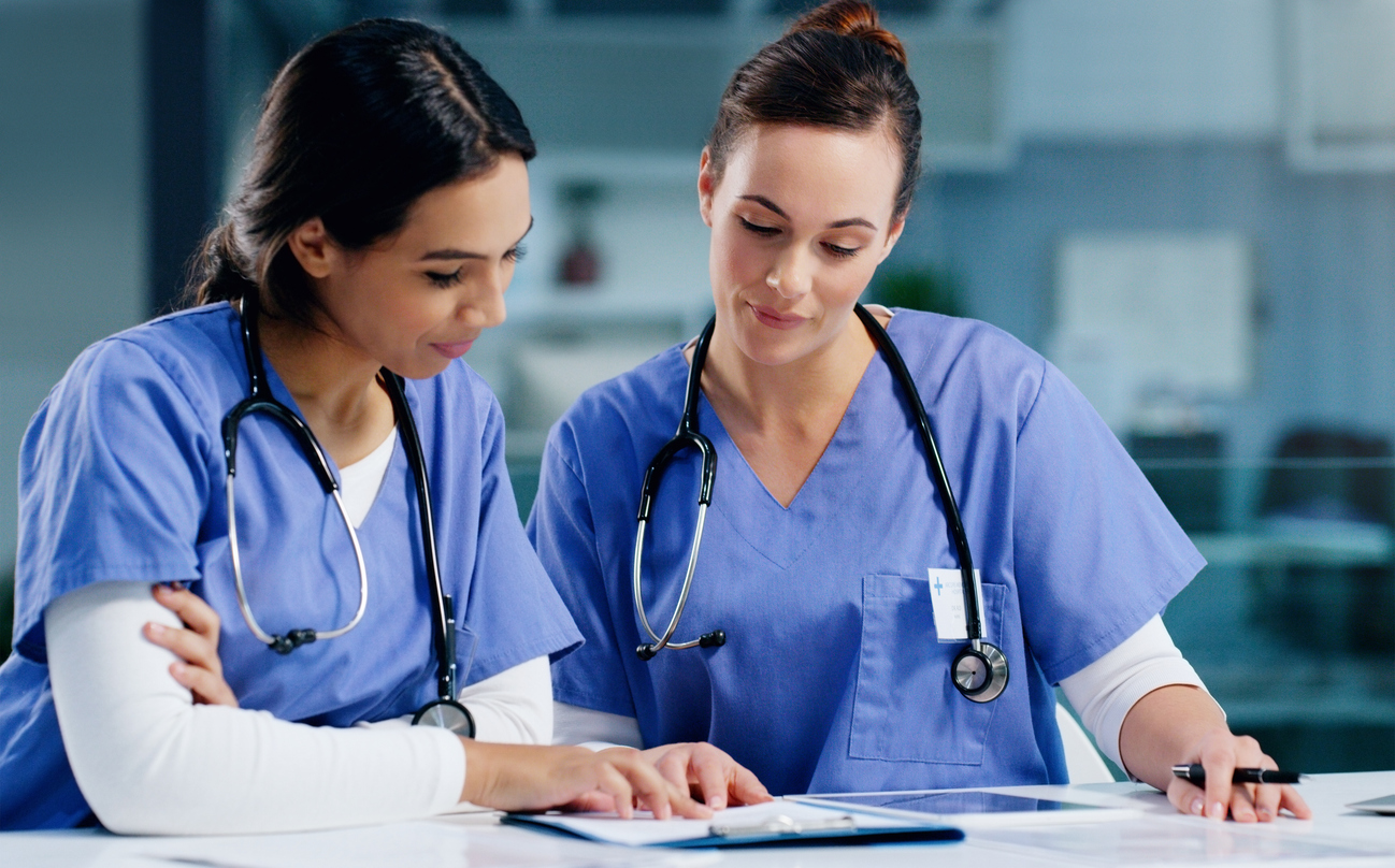 Two nurses looking at a clipboard.