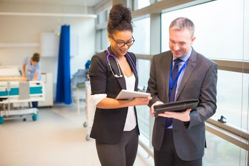 A hospital administrator and a care provider meet in a hospital hallway.