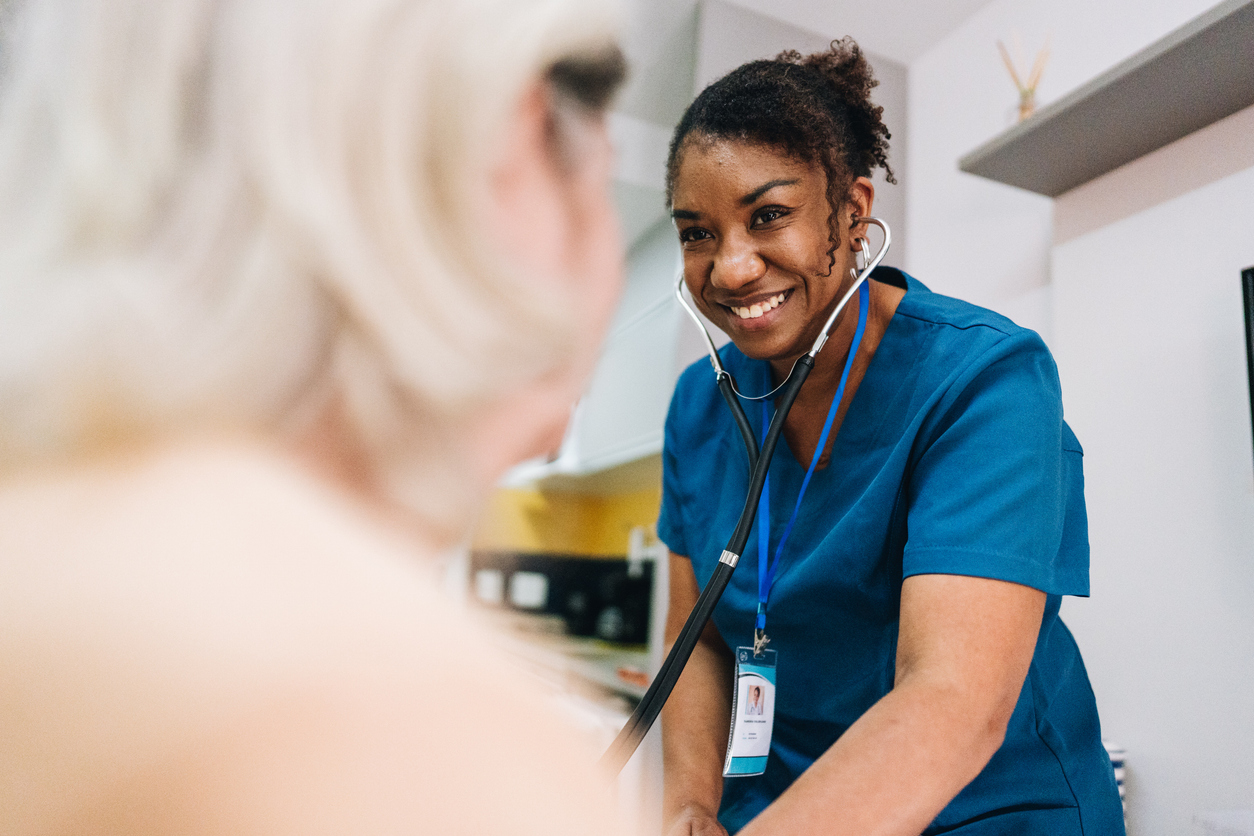 Nurse with a stethoscope smiling treating a patient.