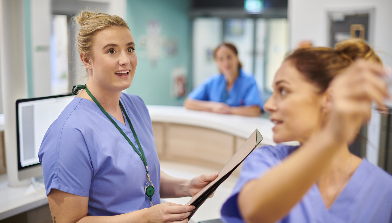 Nurses in Scrubs Talking on a Hospital Floor.