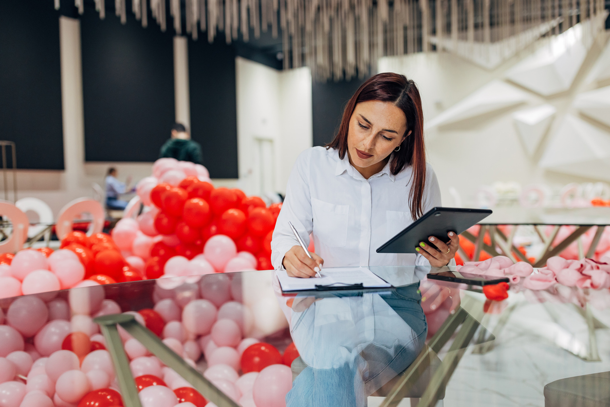 An event planner works on a tablet in a room full of balloons.