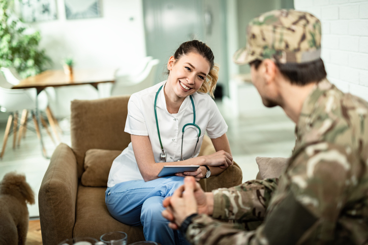 A veteran wearing a uniform, sitting with a nurse. 