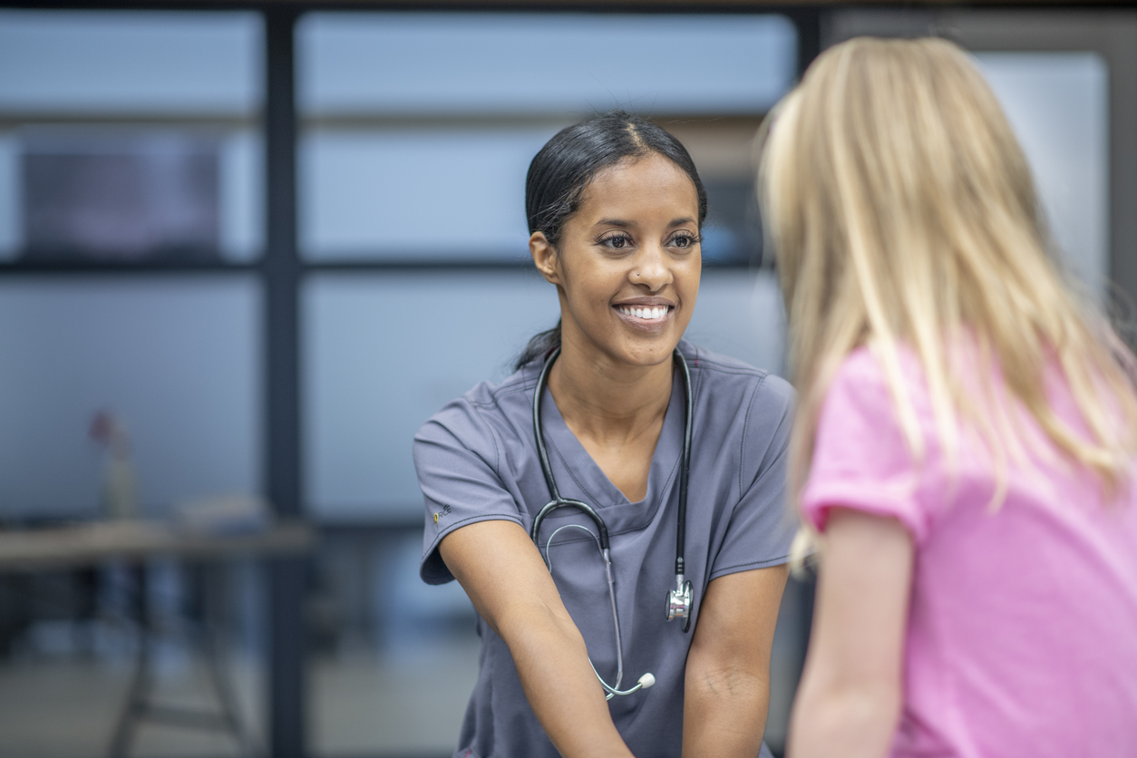 A school nurse smiles at a young patient.