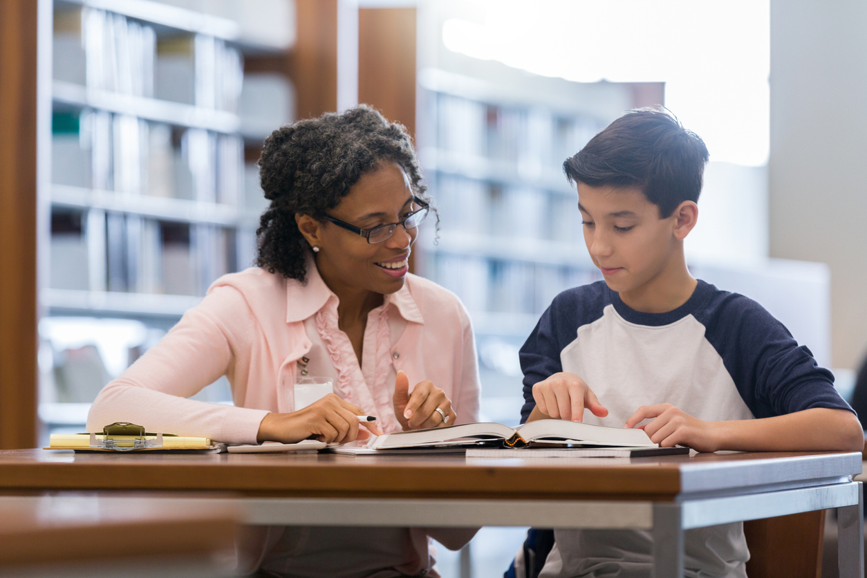 A teacher helps a student read.