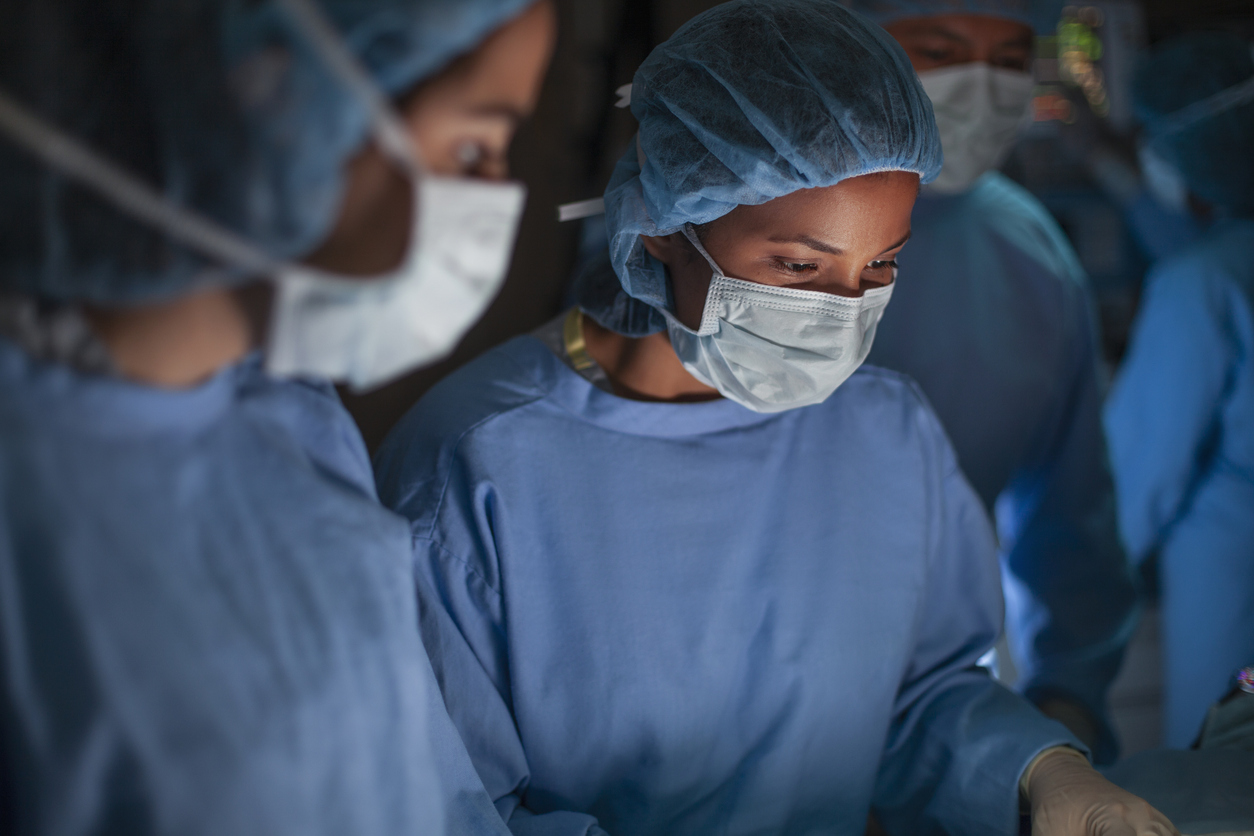Perioperative Nurse Wearing Scrubs in an Operating Room Working With Other Nurses.