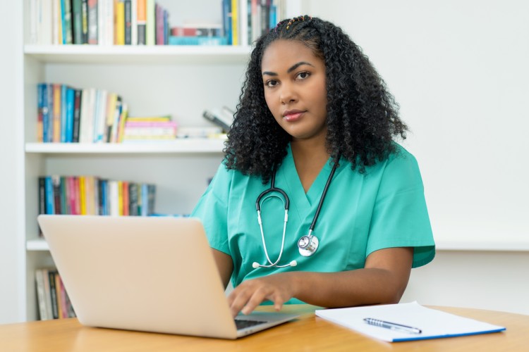 A nursing student works on a laptop.