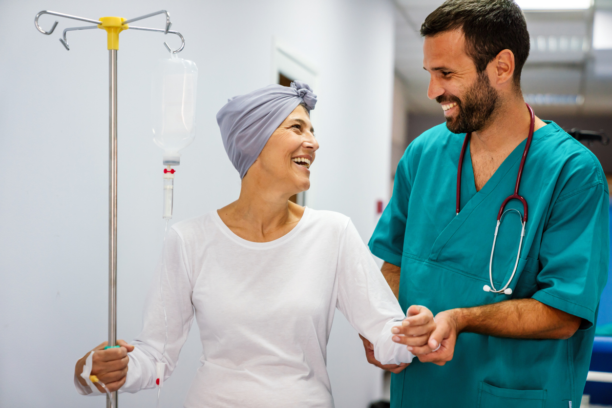 An oncology nurse smiles and helps a patient in a medical facility. 