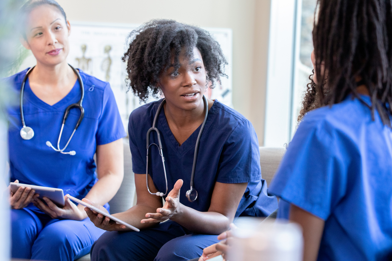 Several nurses meet in the hospital for a peer review session.