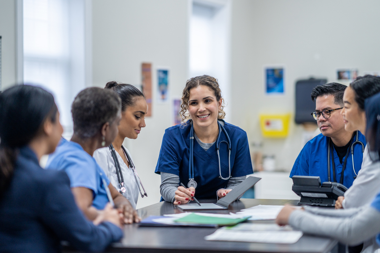 A Group of Nurses and Medical Professionals Meet at a Table.