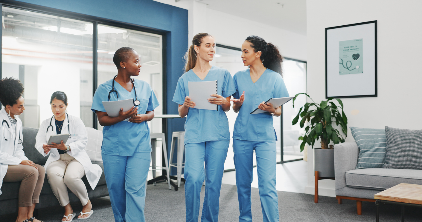 Three nurses walking and talking in a medical facility.