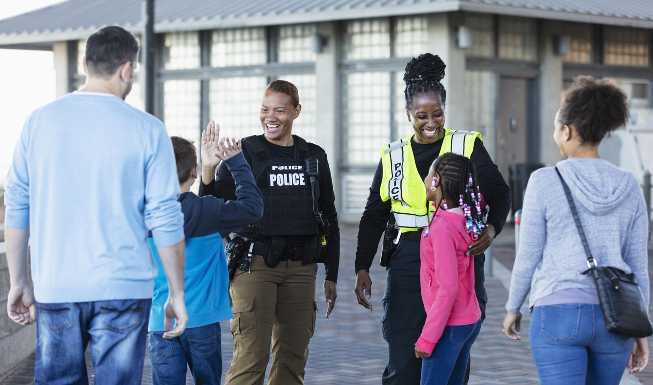 Two police officers talk to children and their parents in the community.