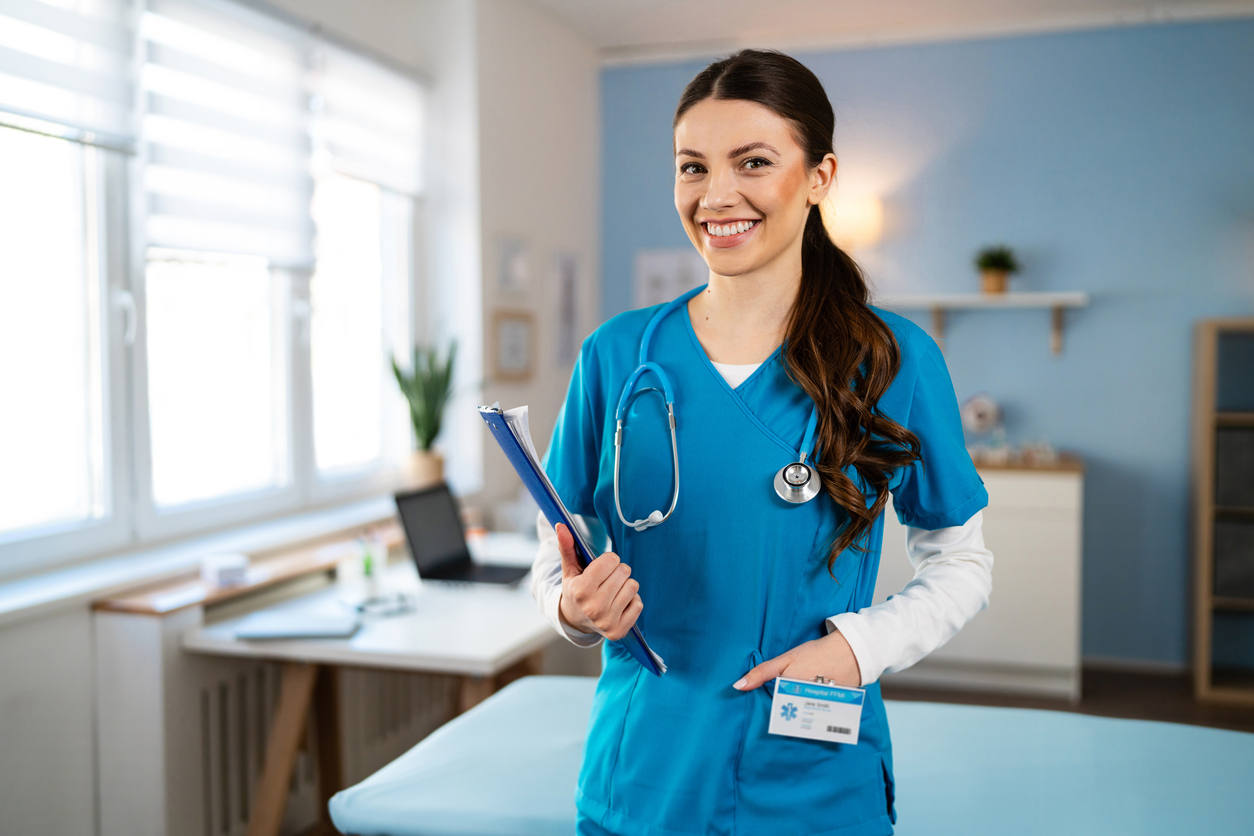 A nurse holds patient files while regarding the camera.