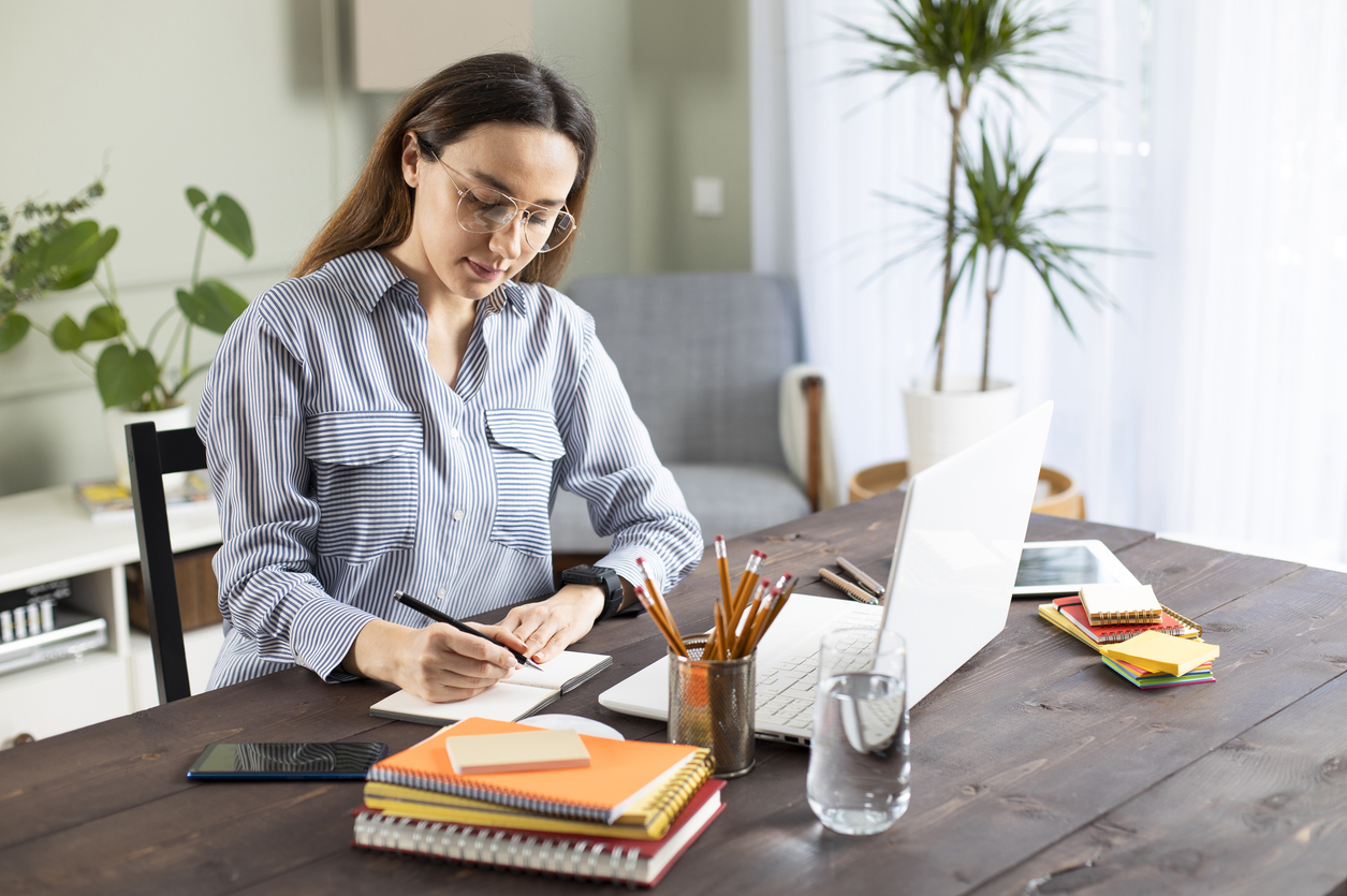 A freelance medical writer works on a laptop in a home office.