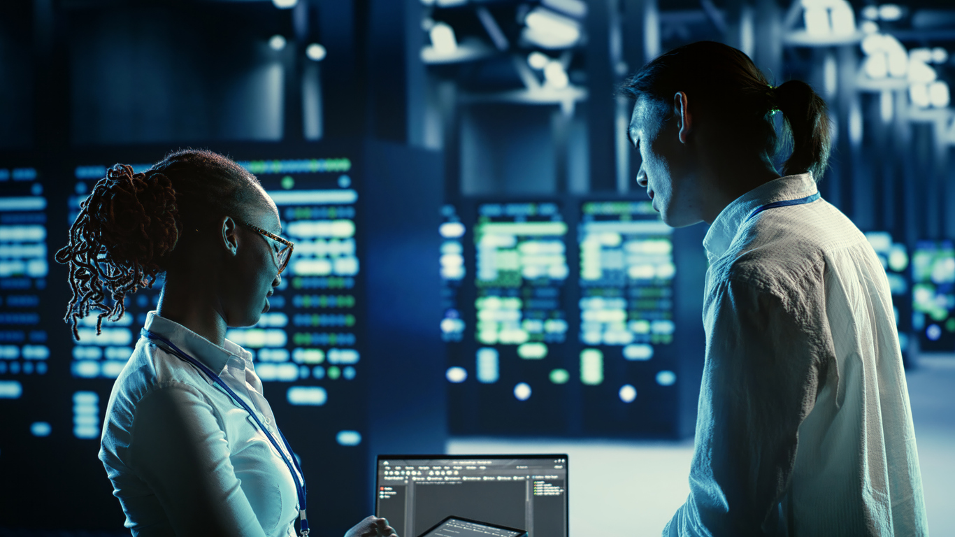 Cybersecurity professionals looking at a computer in a control room. 