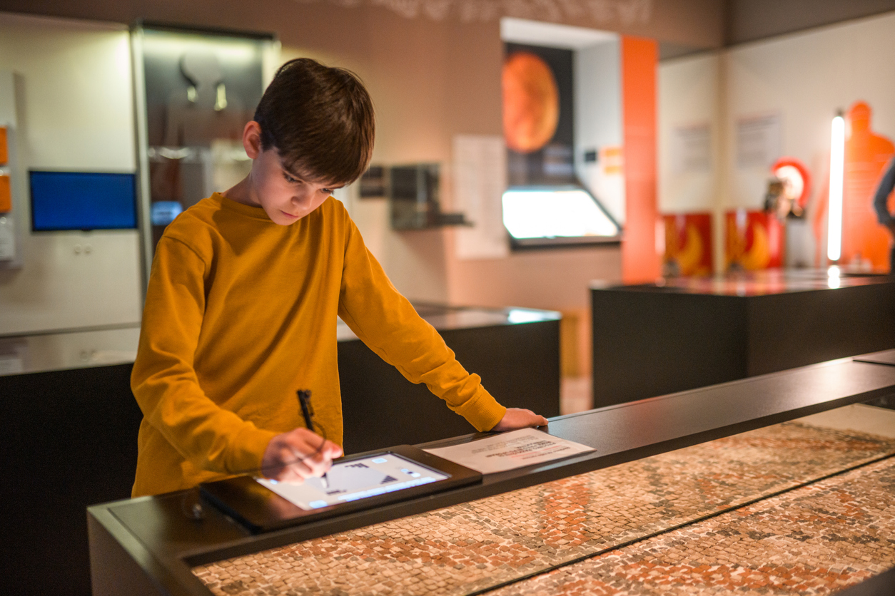 A child uses an interactive table at a history museum.