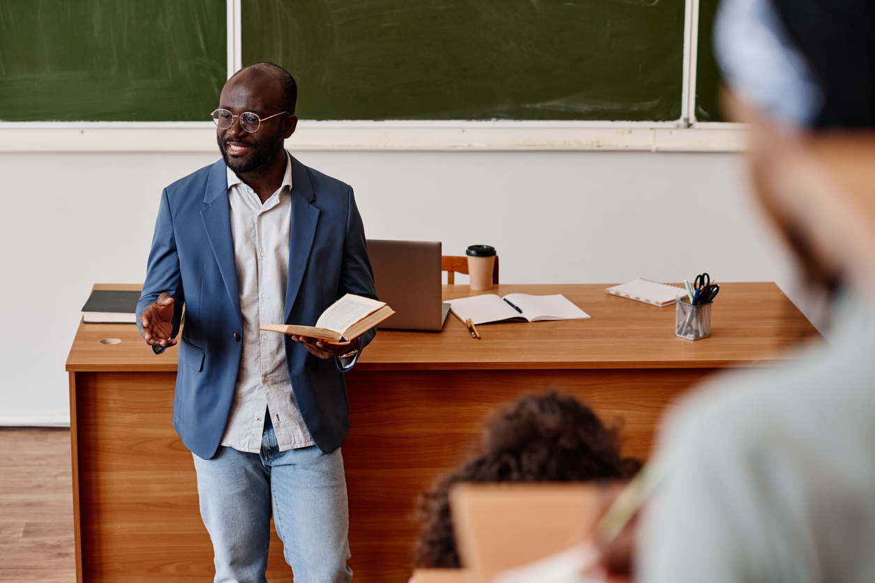 An Adjunct Professor Holding a Book Gives a Lecture.