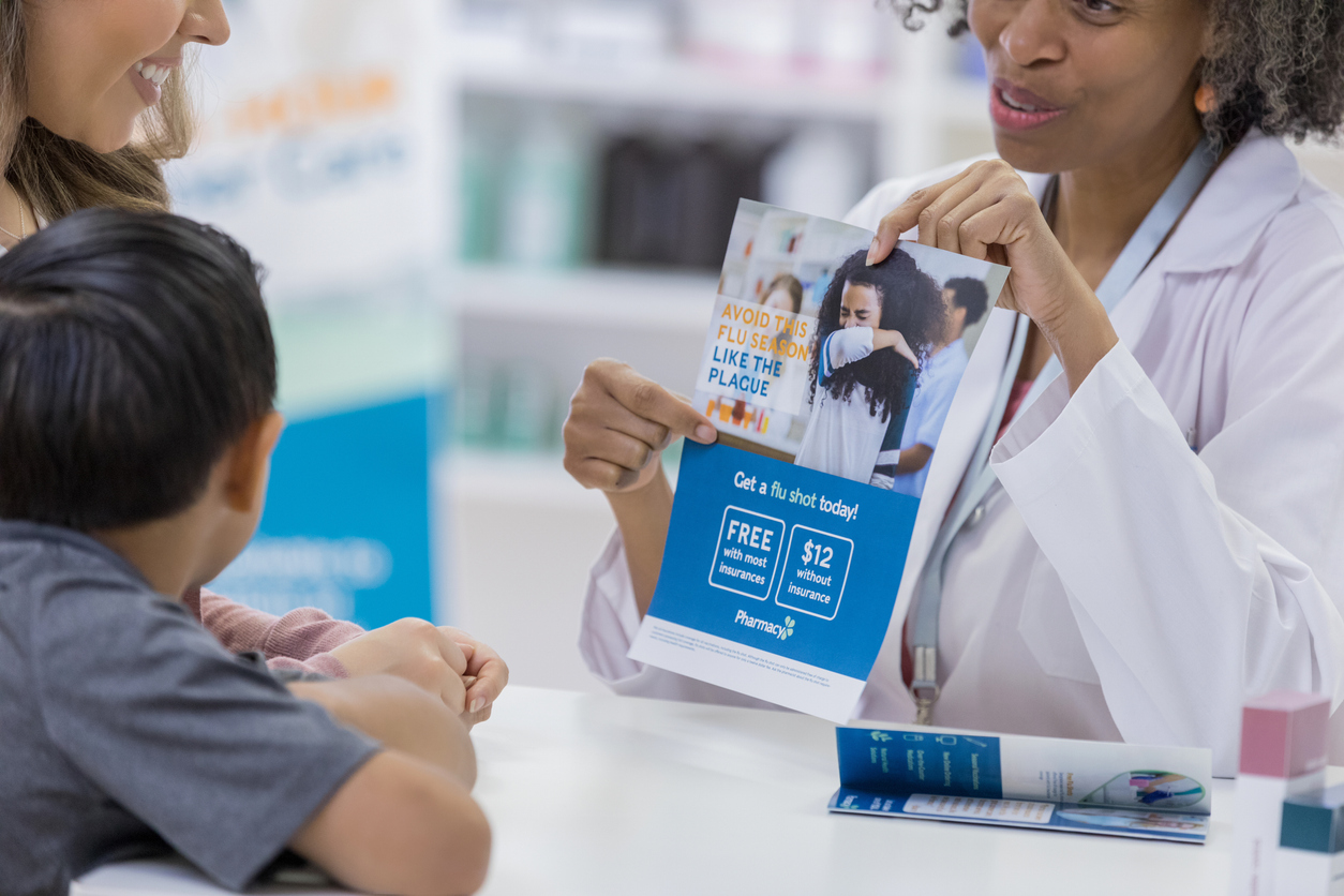 A nurse shows a pamphlet on flu prevention to a parent and child.