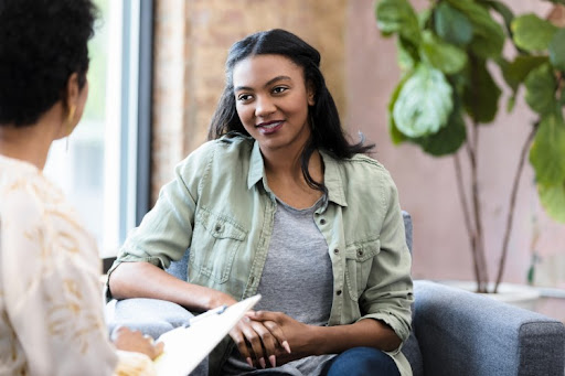 A counselor holding a clipboard talks to a smiling client.