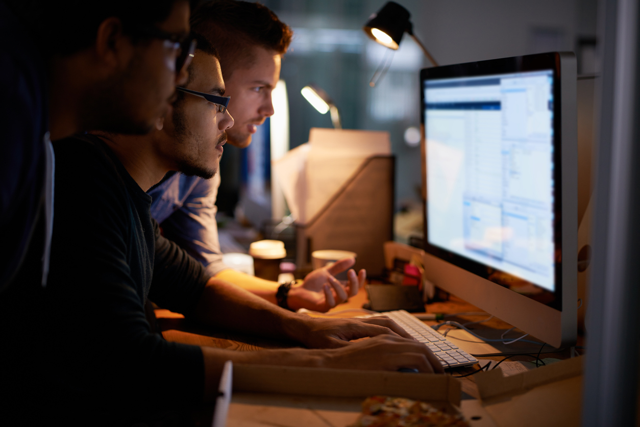 Three Network Security Professionals Working Together on a Monitor.