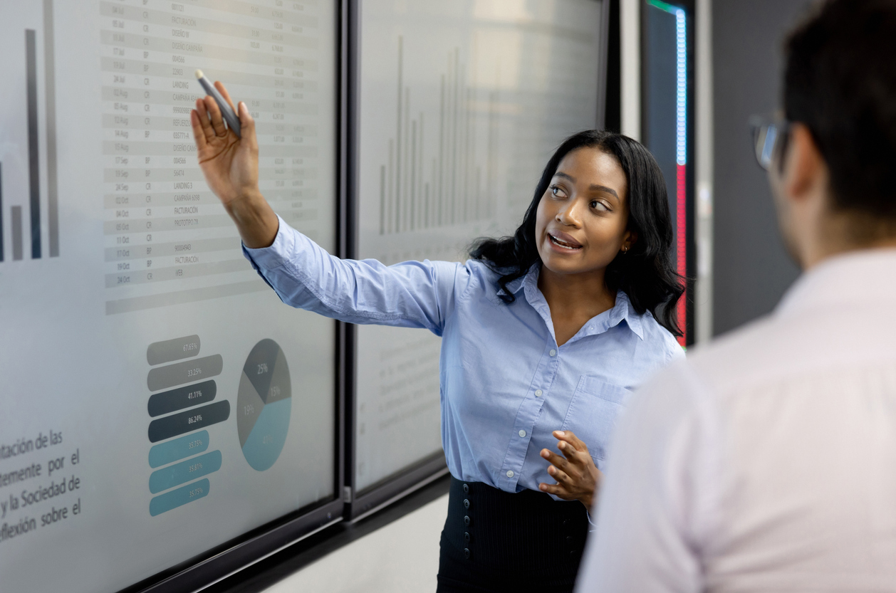 A security risk analyst stands in front of a screen presenting statistics.