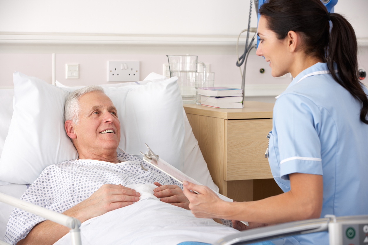 Bedside nurse sitting with a patient in a medical facility. 