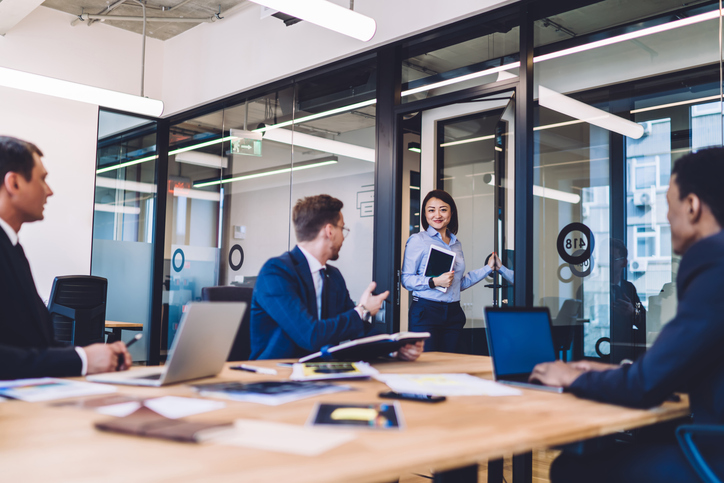 A cybersecurity consultant entering a conference room where business people are seated.