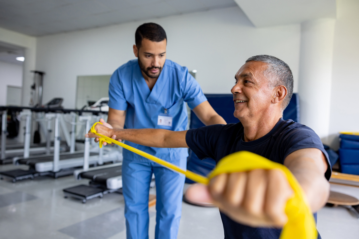 An Occupational Therapy Assistant Guides a Patient Using a Stretch Band.