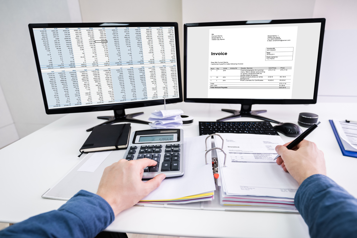  An accountant uses a calculator and computer to check invoices against the entries in a spreadsheet.
