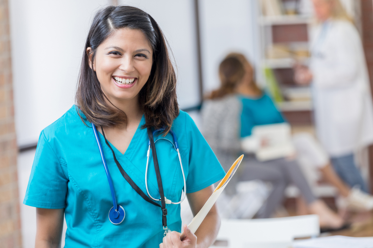 Nurse standing in a medical facility with a folder about to meet with patients. 