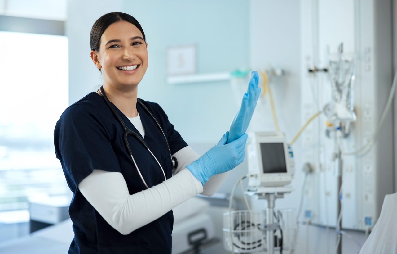 A Nurse Smiling and Putting on Gloves in a Medical Facility.