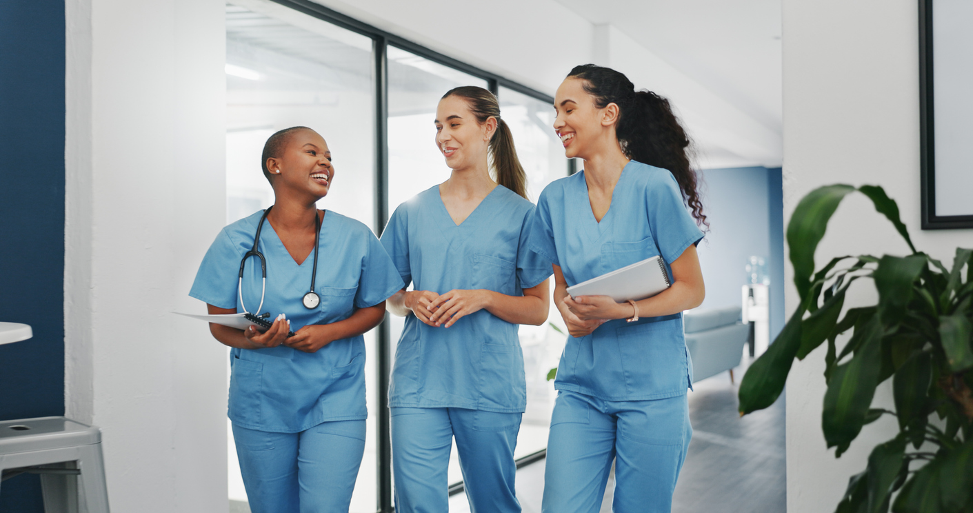 Nurses walking together and laughing in a medical facility.
