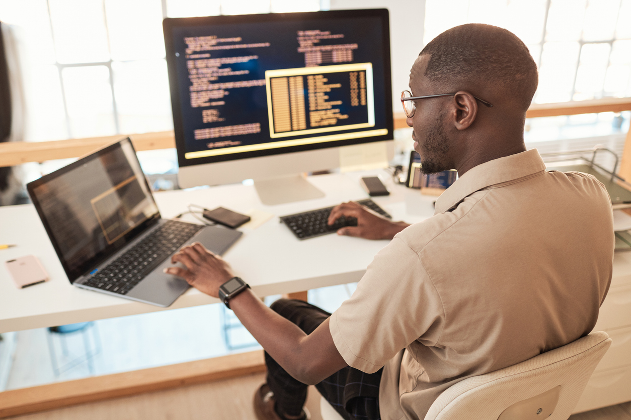 A cybersecurity professional reviews code on a laptop.