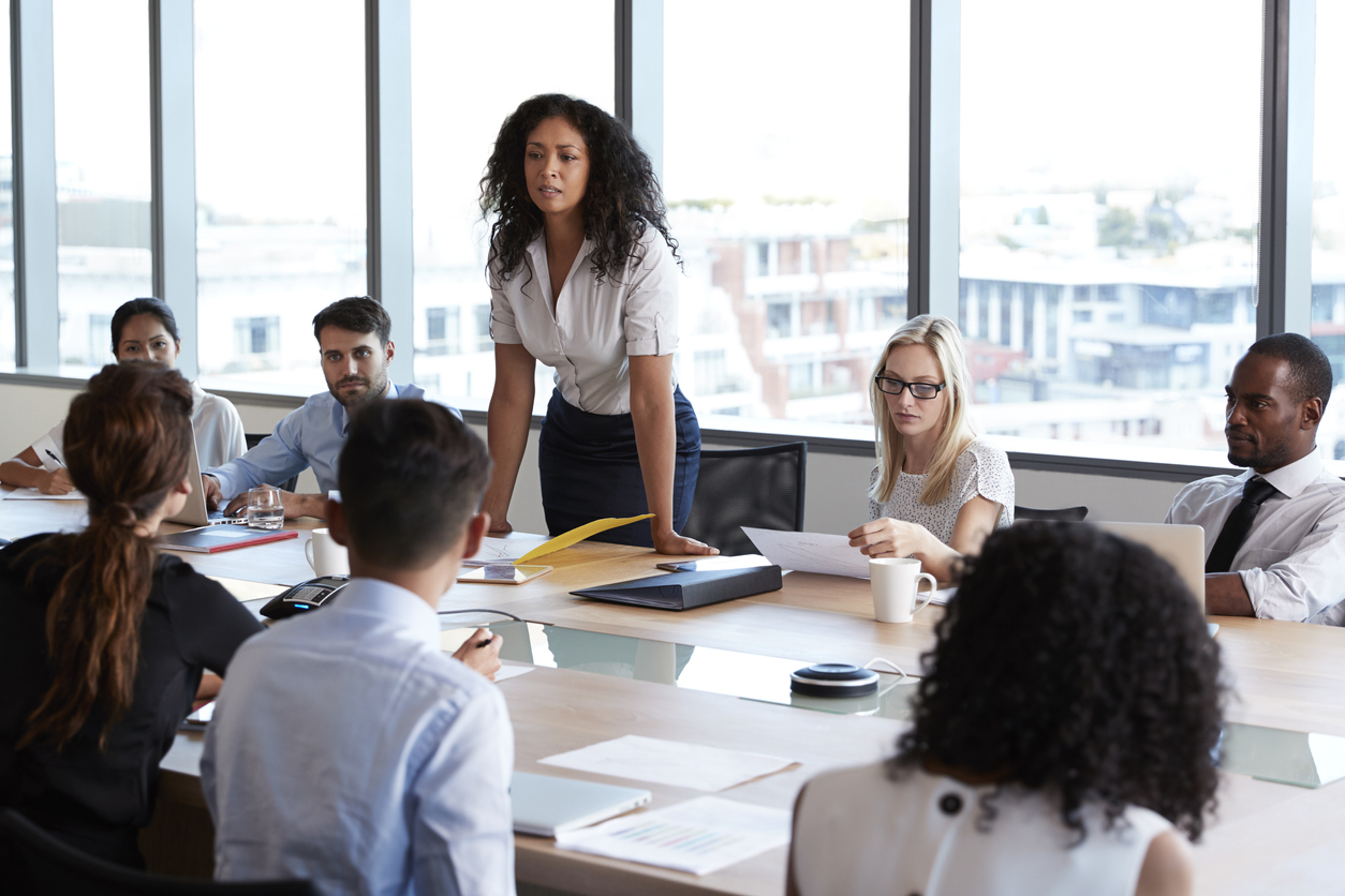 A sales manager directs a staff meeting at a conference table.