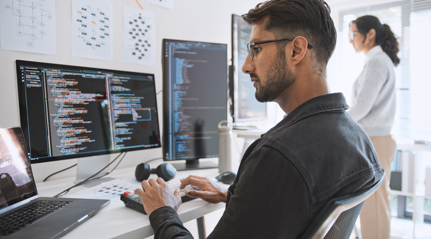 Cybersecurity Professionals Review Code on Monitors.