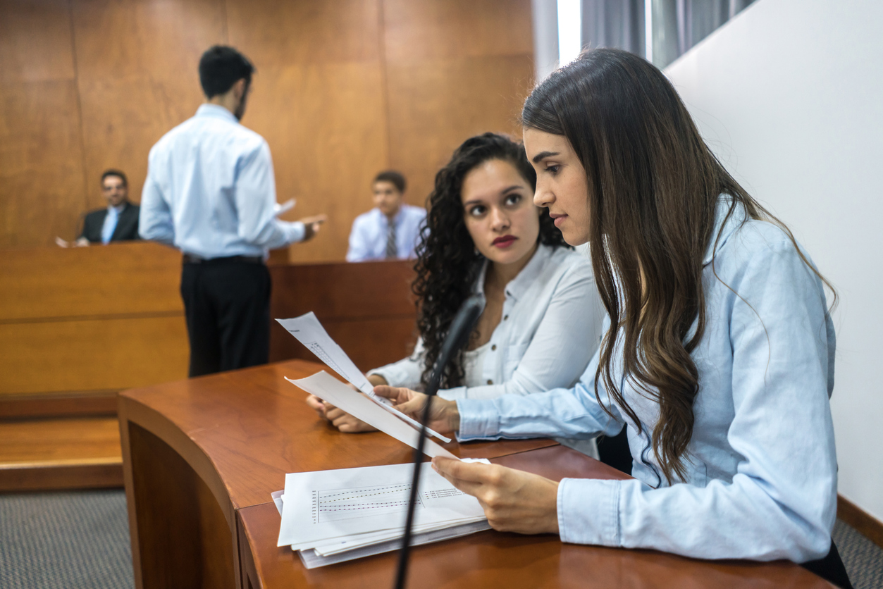 A Court Interpreter Reviews Documents for a Client in a Courtroom.