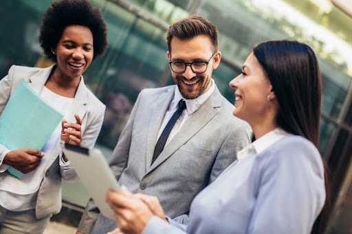 Three smiling business people meet to discuss a project.