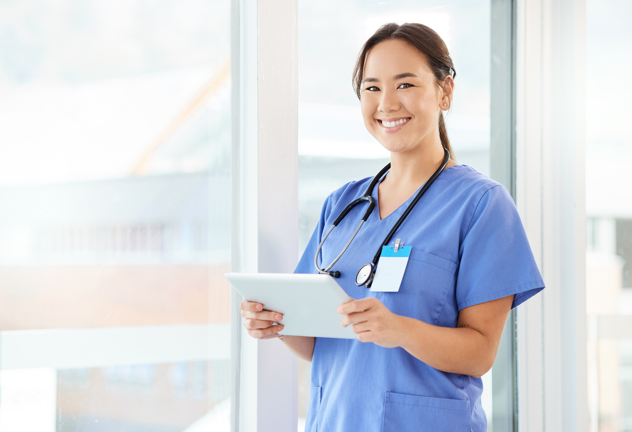 A smiling nurse holds a tablet.