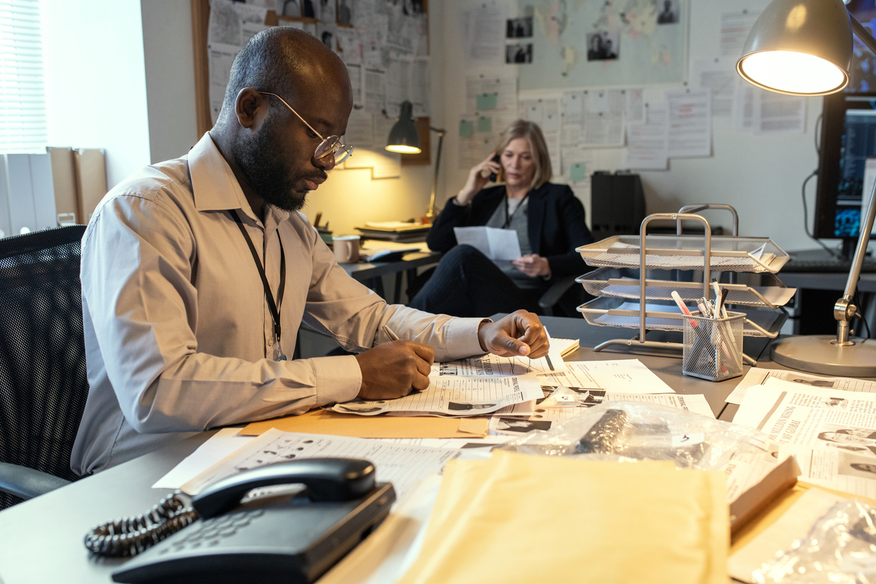 A Detective Makes Notes About an Investigation While Sitting at a Desk.