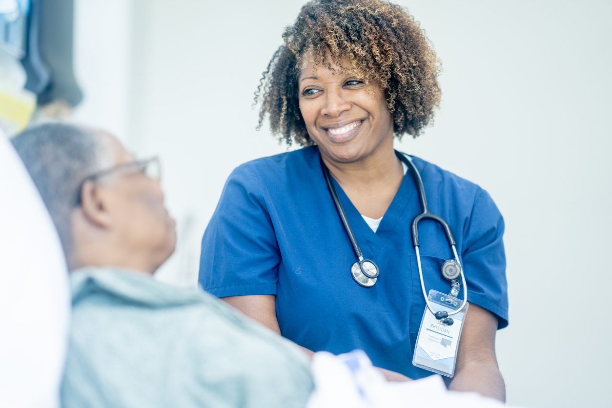 A smiling nurse tends to a patient in a hospital bed.