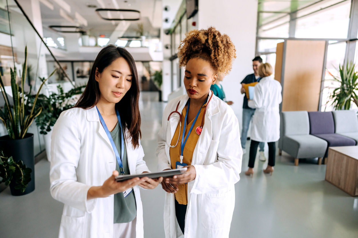 A Nurse Administrator Reviews Data on a Tablet With Another Nurse Leader.