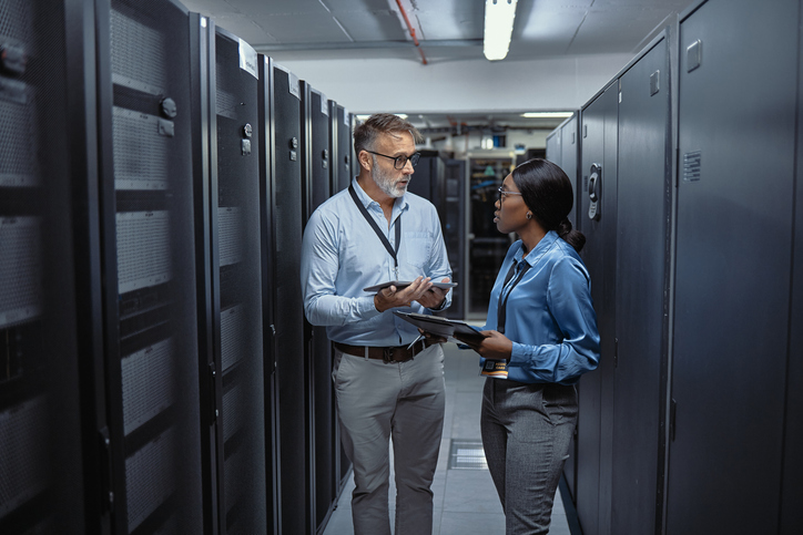 Two cybersecurity professionals at work in a server room.