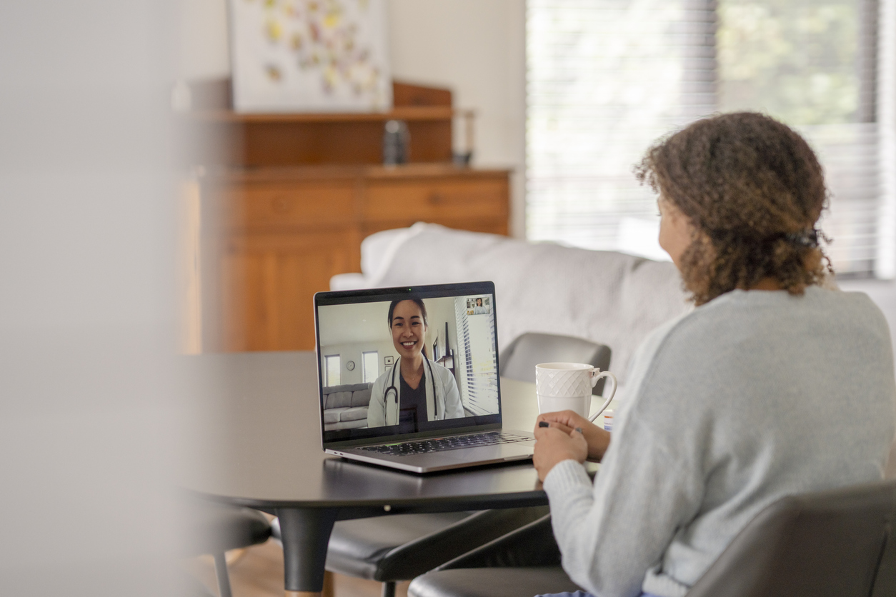 A patient consults with a caregiver via videochat on a laptop.