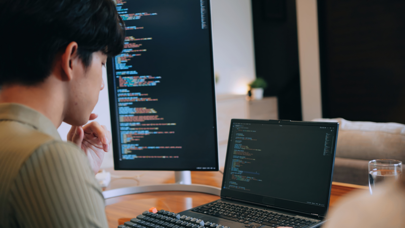 A Data Privacy Officer Reviews Code on Dual Screen Monitors.