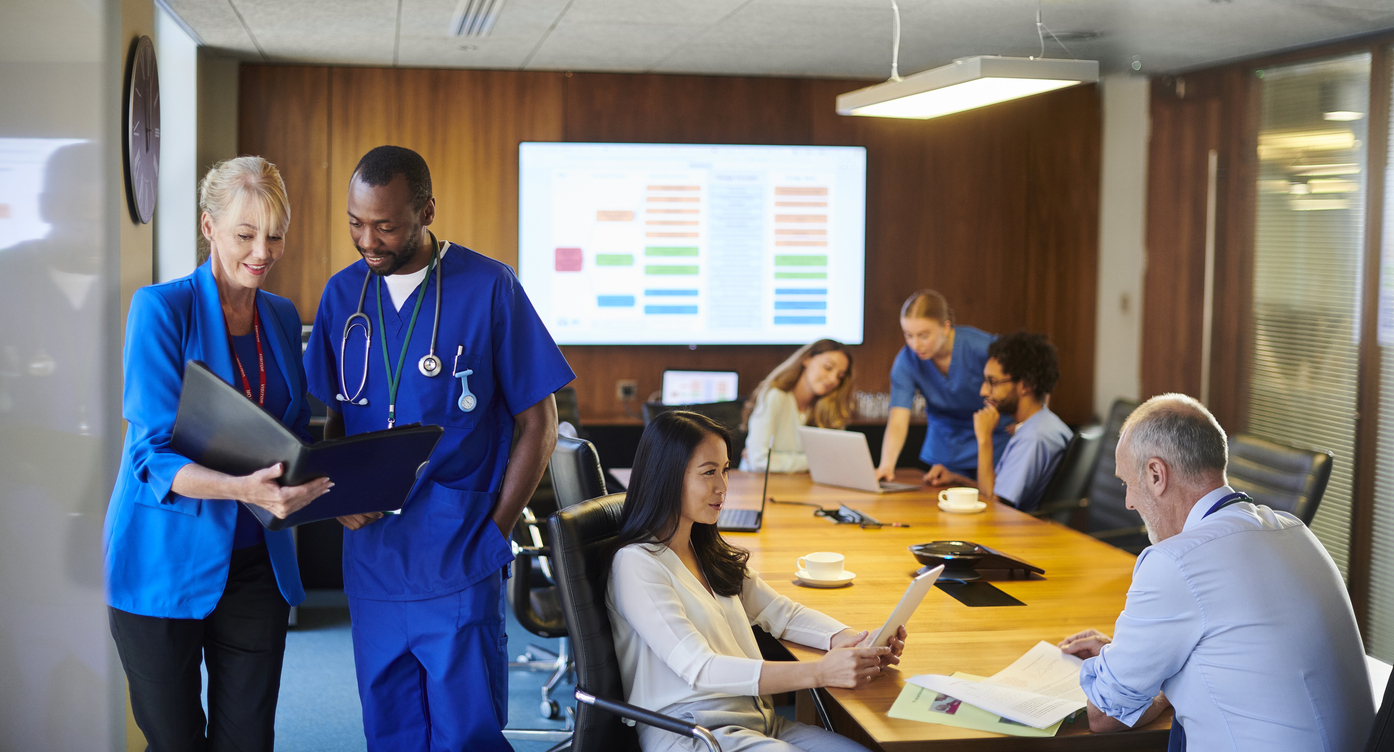 A Clinical Director Goes Over Staffing Needs With a Doctor After a Meeting in the Hospital Board Room.