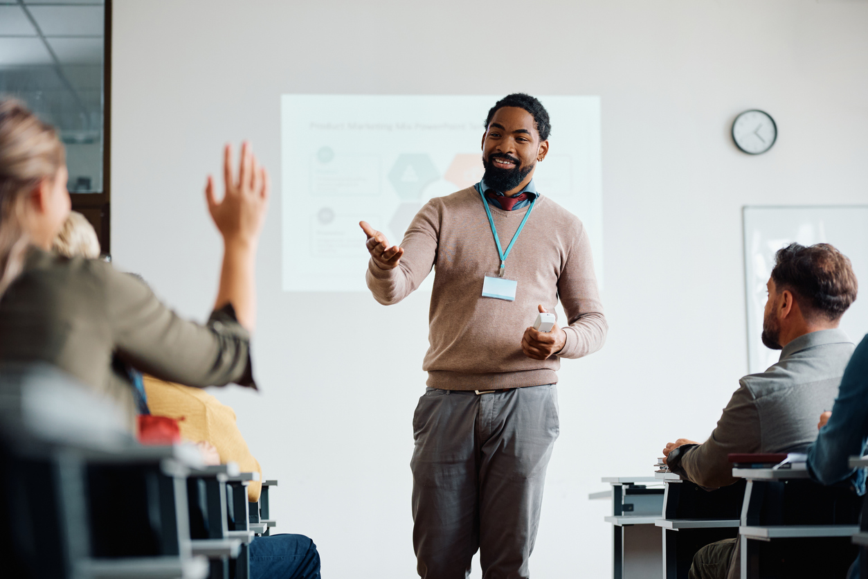 An adult education instructor calls on a student in a classroom.